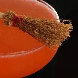 A red cocktail garnished with a miniature witch's broom