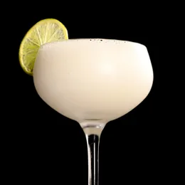 A creamy, pale cocktail in a coupe with a lime wheel